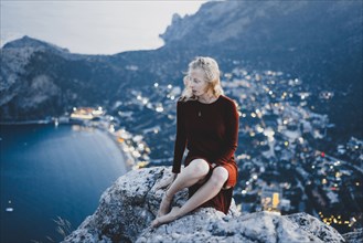 Caucasian woman sitting on rock near ocean