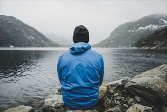 Caucasian man sitting on rocks admiring lake