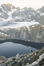 Caucasian man sitting on rock admiring scenic view of mountain lake