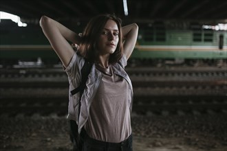Caucasian woman stretching arms near train tracks at night