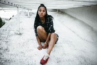 Portrait of serious African American woman sitting on concrete