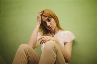 Pensive Caucasian woman leaning against wall