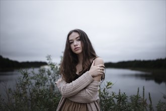 Portrait of serious Caucasian woman standing near a river
