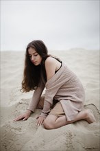 Caucasian woman kneeling in sand
