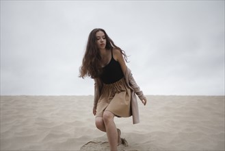 Caucasian woman crouching at beach