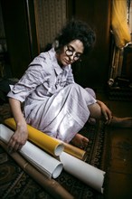 Caucasian woman sitting on floor with rolled up paper