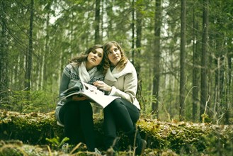 Caucasian women reading magazine in forest