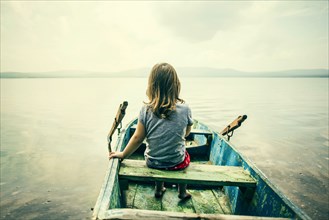 Caucasian girl sitting in boat on still lake