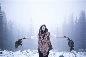 Caucasian woman holding tree branches in snowy woods