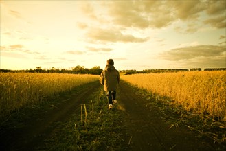 Mixed race child walking on path through rural field