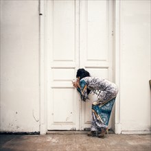 Caucasian woman peering through keyhole