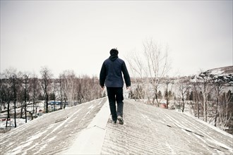 Caucasian man walking on snowy roof