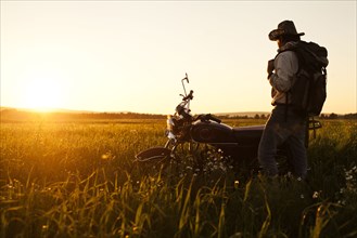 Mari man standing in field with motorcycle