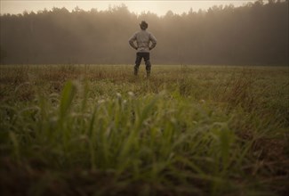 Mixed race man standing in field in rural landscape