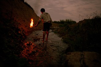 Mari man holding torch in rural creek