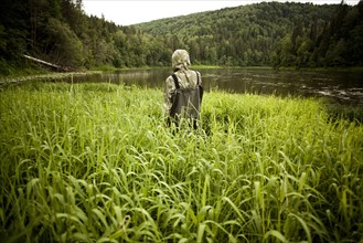Mari man in wading boots standing in tall marsh grass