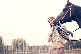Caucasian woman petting horse near lake