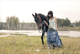 Caucasian woman leading horse near lake