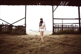 Caucasian woman walking on hay in barn