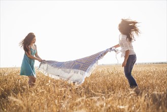 Caucasian women spreading blanket in rural field