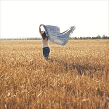Caucasian woman carrying blanket in rural field