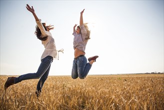 Caucasian women jumping for joy in rural field