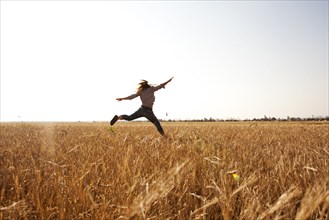 Caucasian woman jumping for joy in rural field