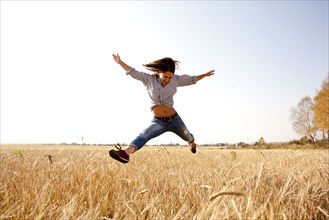 Caucasian woman jumping for joy in rural field