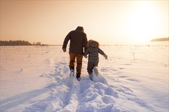 Mari father and son walking in snowy field