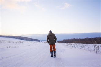 Mixed race man walking in snowy field