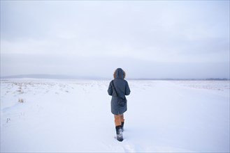 Caucasian woman walking in snowy field