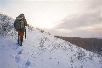 Mixed race man walking on snowy hillside