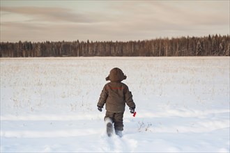 Mari boy walking in snowy field
