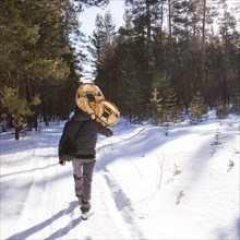 Mari man carrying snowshoes on snowy path