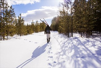 Mari man carrying skis on snowy path