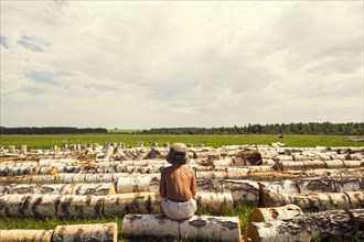 Mari boy sitting on log in rural field