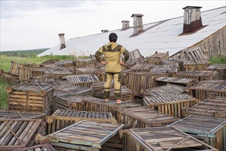 Mari man standing on wooden crates near roof