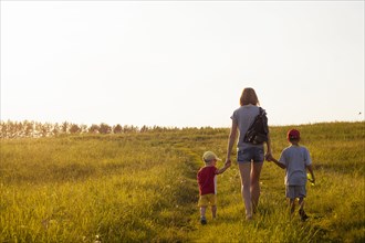 Mother and sons walking in rural field