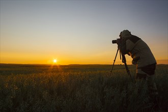 Mixed race man photographing rural sunset