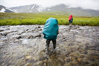 Backpackers crossing remote stream