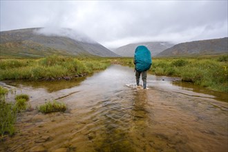 Mari backpacker walking in remote stream