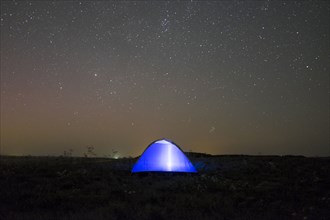 Glowing tent under starry night sky