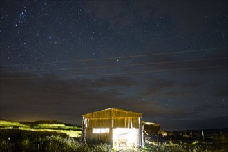 Illuminated cabin under starry night sky