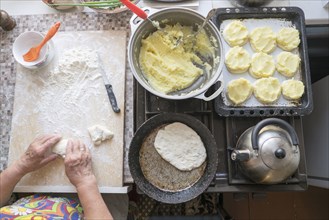 Caucasian woman kneading dough on cutting board near stove
