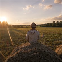 Mari man sitting on hay bale at sunset