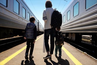 Mother and sons walking between trains at train station