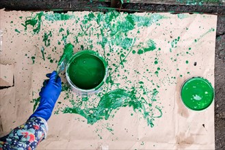 Hand of Caucasian woman splashing green paint on paper