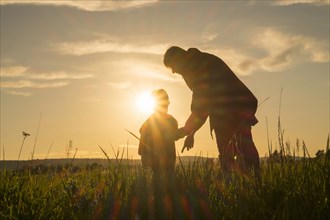 Woman and son standing in field at sunset