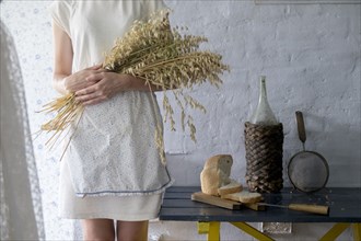 Caucasian woman holding bouquet of wheat near sliced bread