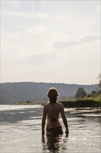Caucasian woman standing in lake wearing bikini